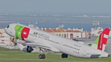 Lizbon, Portekiz - 25 Şubat 2025: Lizbon Havaalanı 'ndan kalkan uçak. TAP Air Portugal uçaklarının yakın çekim görüntüleri şehrin ufuk çizgisi ve havaalanı altyapısı ile birlikte pistten kalkıyor.