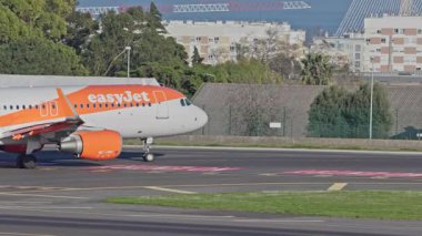 Lizbon, Portekiz - 25 Şubat 2025: Lizbon Havaalanı 'na indikten sonra terminallere giden ticari uçak. EasyJet Havayolları şehrin silueti ve havaalanı altyapısı ile taksiyollarına devam ediyor