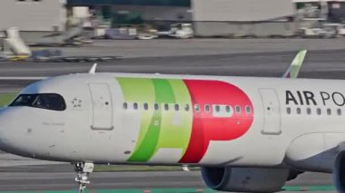 Lizbon, Portekiz - 25 Şubat 2025: Lizbon Havaalanı 'ndan kalkan uçak. TAP Air Portugal uçaklarının yakın çekim görüntüleri şehrin ufuk çizgisi ve havaalanı altyapısı ile birlikte pistten kalkıyor.