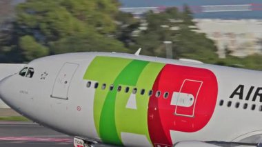 Lizbon, Portekiz - 25 Şubat 2025: Lizbon Havaalanı 'ndan kalkan uçak. TAP Air Portugal uçaklarının yakın çekim görüntüleri şehrin ufuk çizgisi ve havaalanı altyapısı ile birlikte pistten kalkıyor.