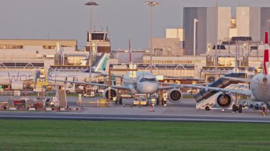 Lizbon, Portekiz - 25 Şubat 2025: Gün batımında Lizbon Havaalanı 'nda TAP Air Portugal uçağı çekilmektedir. Uçak kalkış için hazırlandı. Terminal ve diğer uçaklar görülebilir durumda.