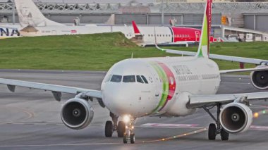 Lizbon, Portekiz - 25 Şubat 2025: Meşgul bir Lizbon havaalanındaki TAP Air Portugal taksileri, terminaller, diğer uçaklar ve arka planda bir şehir manzarası. Canlı.