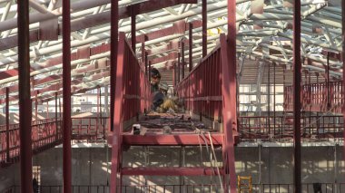 Welders working with electrode at semi-automatic arc welding metal reinforcement on a construction site timelapse. Workers in uniform and scaffolding