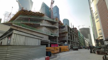 İnşaat alanındaki vinçler, modern gökdelenlerle çevrili. Zaman kavramları aşırı hızlanıyor. Büyük bir şehirde sanayi kenti manzarası