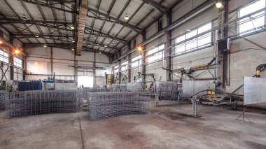 Kaynakçılar üretim tesisi zaman ayarında yarı otomatik kaynaklamada elektrot ile çalışıyorlar. Üniformalı bir işçi ve fabrikada metal takviyesi.