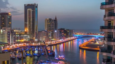 Dubai Marina kulelerinin havadan görünüşü yatları ve trafiği ile köprüden geceye geçiş, Birleşik Arap Emirlikleri. Çatıdan görüntüyü izle. Dubai Marina, Dubai 'de bir şehirdir..