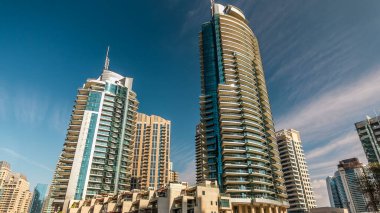 Dubai Marina modern uzun kuleleri, Birleşik Arap Emirlikleri 'ndeki gezinti zamanlarından suya yansıdı. Dubai 'de bir bölge ve yapay bir kanal. Mavi bulutlu gökyüzü