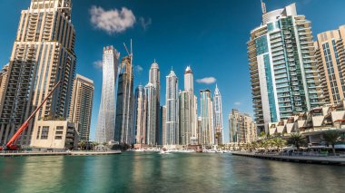 Dubai Marina modern yüksek kuleleri, Birleşik Arap Emirlikleri 'ndeki gezinti zamanı aşırı hızından dolayı suya yansıdı. Dubai 'de bir bölge ve yapay bir kanal. Mavi bulutlu gökyüzü