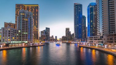 Dubai Marina rıhtımı, Dubai 'deki köprüden gece vardiyasına kadar uzanan kuleleri ve yatları olan Birleşik Arap Emirlikleri. Gün batımından sonra yapay kanallı bölge