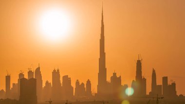 Akşam saatlerinde Dubai şehir merkezinin ufuk çizgisi ile gün batımı. Çölde inşa edilmiş modern gökdelenlerin güzel gökdelenleri. Havaalanı yakınındaki binadan hava görüntüsü