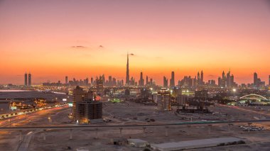 Dubai şehir merkezinin silüeti günden geceye geçiş zamanı. Çölde inşa edilmiş modern gökdelenlerin güzel gökdelenleri. Havaalanı yakınındaki binadan gün batımından sonra hava görüntüsü