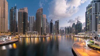 Dubai Marina Kanalı, modern kuleleri ve yatları olan liman kenti Dubai 'deki köprüden gece gündüz geçiş zamanı olan Birleşik Arap Emirlikleri' ne yansıyor. Güneş doğmadan önce etraftaki gökdelenler