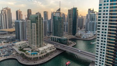 Dubai Marina gezinti güvertesi ve kanalı, gün batımından sonra Dubai, BAE 'de yüzen yat ve tekneler ile gündüz hava manzaralı. Modern kuleler, köprü ve trafik yukarıdan geliyor.