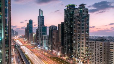 Dubai Kuleleri 'nin şehir merkezinden gece gündüz geçiş zamanı. Gün batımından sonra Şeyh Zayed 'in gökdelenli hava manzarası. Yollarda ve metro hattında trafik vardı. Güzel bulutlu gökyüzü