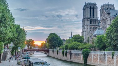Fransa 'daki Notre Dame de Paris Katedrali üzerinde gün batımı manzarası. Başpiskoposluk Köprüsü 'nden hava görüntüsü. Tekne istasyonu ve rıhtım. Mimari ve çarpıcı gökyüzü simgeleri.
