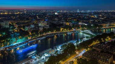 Paris City ve Seine nehrinin gece görüş açısı Eyfel Kulesi gözlem güvertesinin tepesinden geçen teknelerle dolu. Akşam aydınlatması. Yollarda trafik