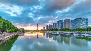 Eyfel Kulesi, Seine Nehri 'nde ve Fransa' nın Paris şehrinde teknelerle gün doğumu zamanı. Mirabeau Köprüsü 'nden gökyüzü dramatik bir şekilde görünüyor. Modern binalar ve yol trafiği. Özgürlük Anıtı