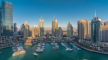 Dubai Marina gökdelenleri, hava zaman çizelgeleri, lüks yatları ve marina gezinti güvertesi olan liman, Dubai, Birleşik Arap Emirlikleri. Gölgeler gün batımında hareket eder