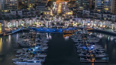 Dubai Marina Fıskiyesi, gece uçuş saati, lüks yatları ve marina gezinti güvertesi olan liman, Dubai, Birleşik Arap Emirlikleri. Aydınlatılmış avuçlar ve yol trafiği