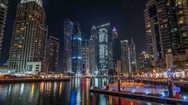 Dubai Yat Limanı defne yatların bir tekne timelapse hyperlapse. En yüksek gökdelenler gece ışıklı kanal suya yansıyan