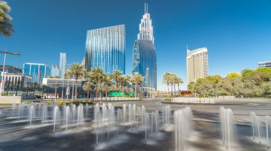 Çeşmeler en yüksek gökdelen timelapse hyperlapse, Dubai ana girişe yakın. Palmiye ve arka plan üzerinde modern kuleli güneşli gün, downtown Dubai yolda trafik