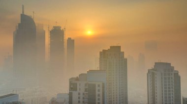 Sisli sabah gündoğumu Dubai timelapse şehir merkezinde. Şehir gökdelenler fütüristik görünümünü sis kaplı. Çatı modern kuleli havadan görünümden. Dubai, Birleşik Arap Emirlikleri