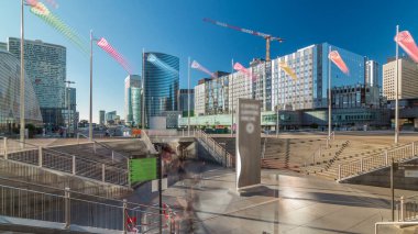 La Defence zaman atlaması panoraması, yüksek gökdelenleri olan iş ve finans bölgesi güneş yansıtmalı binalar ve metro istasyonundan çıkışı olan vinçler
