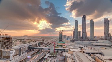 Alışveriş merkezi nin gün doğumu havadan görünümü ve şehir merkezinden vinçler ile inşaat altında bina ile trafik sabah timelapse, renkli gökyüzü. Arka planda Dubai Creek limanı