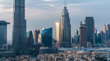 Dubai Şehir Merkezi 'nin ufuk çizgisi gün batımından gece saatlerine kadar Dubai, Birleşik Arap Emirlikleri' nin tepesinden panoramik manzaralı kulelerle dolu. Güneş gökdelenden yansıyor. Çember yollarda ve çeşmelerde trafik