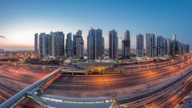 Dubai Marina 'dan Sheikh Zayed yoluna gece gündüz aydınlık gökdelenler ile hava panoramik görüntüsü, geçiş zamanı, Dubai. Trafik, köprüler ve metro istasyonu. Birleşik Arap Emirlikleri