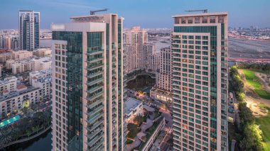 Yeşillik bölge hava görüntüsü. Günden geceye geçiş zamanı. Golf sahasının yukarısından aydınlatılmış konut binaları