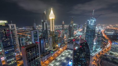Dubai, BAE 'deki tüm gece boyunca Sheikh Zayed Yolu ve DIFC yakınlarındaki binaların panoramik silueti. Finansal merkezde ve şehir merkezinde aydınlık gökdelenler ve modern kuleler