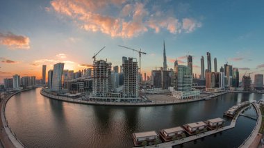 City center at sunset near river with bright illuminated skyscrapers day to night transition aerial timelapse in Business Bay and Downtown, Dubai, United Arab Emirates