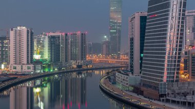 Gece gündüz kanal yakınlarındaki devasa gökdelenlerin hava görüntüsü Business Bay, Dubai, Birleşik Arap Emirlikleri 'ndeki geçiş zamanı..