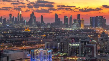 Şehir merkezinde büyük gökdelenler ve onlardan gelen ışıklar ve renkli gökyüzü, Dubai, Birleşik Arap Emirlikleri ile finans bölgesi Timelapse 'nin havadan görünüşü
