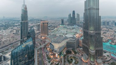 Şehir merkezindeki Dubai 'nin panoramik ufuk çizgisi manzarası alışveriş merkezi, çeşmeler ve Burj Khalifa hava gününden geceye geçiş zamanı. Günbatımından sonra modern gökdelenler ve bulutlu gökyüzü