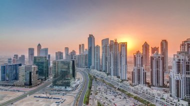 Günbatımında Business Bay, Dubai, Uae 'de bulunan birçok gökdelenle modern yerleşim ve ofis kompleksi. Körfez Bulvarı Parkı 'nın yanındaki büyük otoparkta arabalar ve trafik vardı.