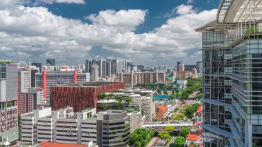 Singapur silueti Victoria caddesi ve Ulusal Kütüphane havadan zaman aralığı hipervanesi. Trafiği olan yeşil ağaçlar. Mavi gökyüzünde bulutlar