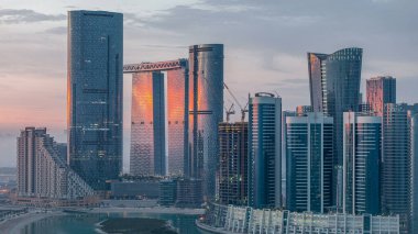 Abu Dabi 'deki Al Reem' deki gökdelenler gün doğumunda gökdelenler. Al Reem Adası 'ndan sabah sisli bir şehir manzarası. Güneş cam yüzeyine yansıyor