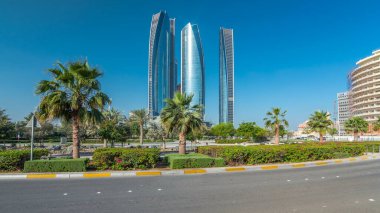 Ebu Dabi 'nin gökdelenleri Etihad Kuleleri' nin binaları zaman atlamalı. Avuç içleriyle ve trafiğiyle park et. Güneş cam yüzeyden yansıyor. Birleşik Arap Emirlikleri