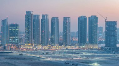 Al Reem 'deki gökdelenler ve Abu Dabi' deki Al Maryah Adası 'ndaki Al-Dabi Adası' ndan gece-gündüz geçiş zamanları yukarıdan gün batımından sonra. Aydınlatılmış binaları olan Al Reem Adası 'ndan havadan şehir manzarası