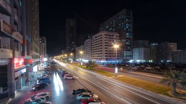 Otoparkı trafikte olan Ajman 'ın şehri. Köprüden hava manzarası, gece vakti aydınlatılmış binalarda ışıklar. Birleşik Arap Emirlikleri.