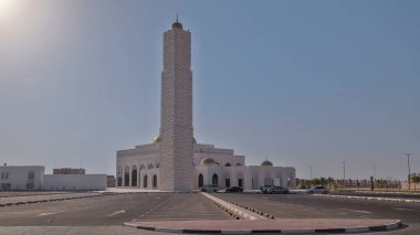 Ajman 'daki beyaz cami, Birleşik Arap Emirlikleri' nin minaresinin üzerinde güneş ile birlikte aşırı hızlanıyor. Binanın önündeki otopark.