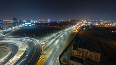 Panorama, Ajman hava sahasında büyük bir kavşakta trafiği gösteriyor. Gece vakti çatıdan görünüyor. Birleşik Arap Emirlikleri 'nde üst geçitle kesişen birçok araba var..