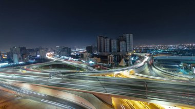 Panorama, Ajman hava sahasında büyük bir kavşakta trafiği gösteriyor. Gece vakti çatıdan görünüyor. Birleşik Arap Emirlikleri 'nde üst geçitle kesişen birçok araba var. Arkaplanda gökdelenler