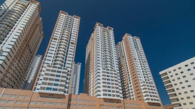 Ajman zaman ayarlı hiperhızlandırılmış modern yeni kuleler. Ajman 'ın yerleşim yeri ve ofis gökdelenleri olan şehir manzarası. Mavi gökyüzü. Birleşik Arap Emirlikleri.