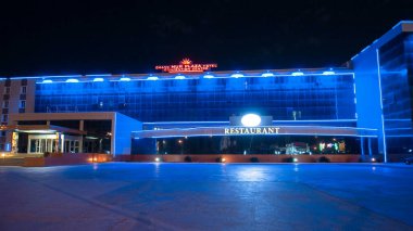 Aktau 'nun otel ve restoranlı gece hiperlapası. Aydınlatılmış Binalar Kazakistan 'ın Canlı Yüreğinde Akşam Gökyüzünü aydınlatıyor