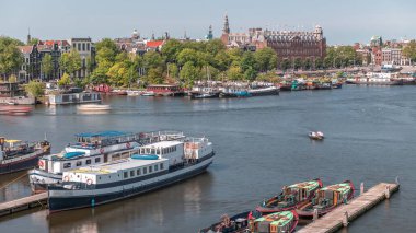 Oosterdok Limanı 'ndaki iskelede botları olan Amsterdam gökyüzü manzarası. Amsterdam Centraal İstasyonu ve Scheepvaarthuis yakınlarındaki geleneksel Hollanda mimarisi. Amsterdam, Hollanda