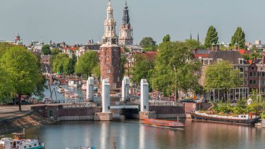 Amsterdam şehri, Montelbaanstoren Kulesi 'nin yer aldığı, kanal boyunca uzanan şehir manzaralı bir zaman çizelgesi. Eski kentteki tarihi Hollanda evleri, köprüler, mavnalar ve yüzen evler