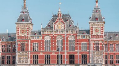 Amsterdam Merkez Tren İstasyonu 'nun zaman çizelgesi yaz günü mavi gökyüzünde bulutlarla kapanıyor. Amsterdam, Hollanda